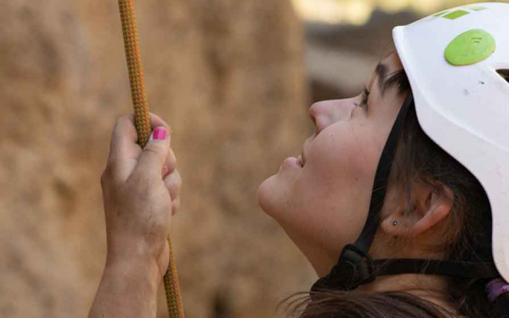 woman looks up while belaying a climbing on course with outward bound